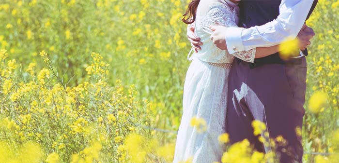 黄色い花畑で男女が抱き合っているイメージ